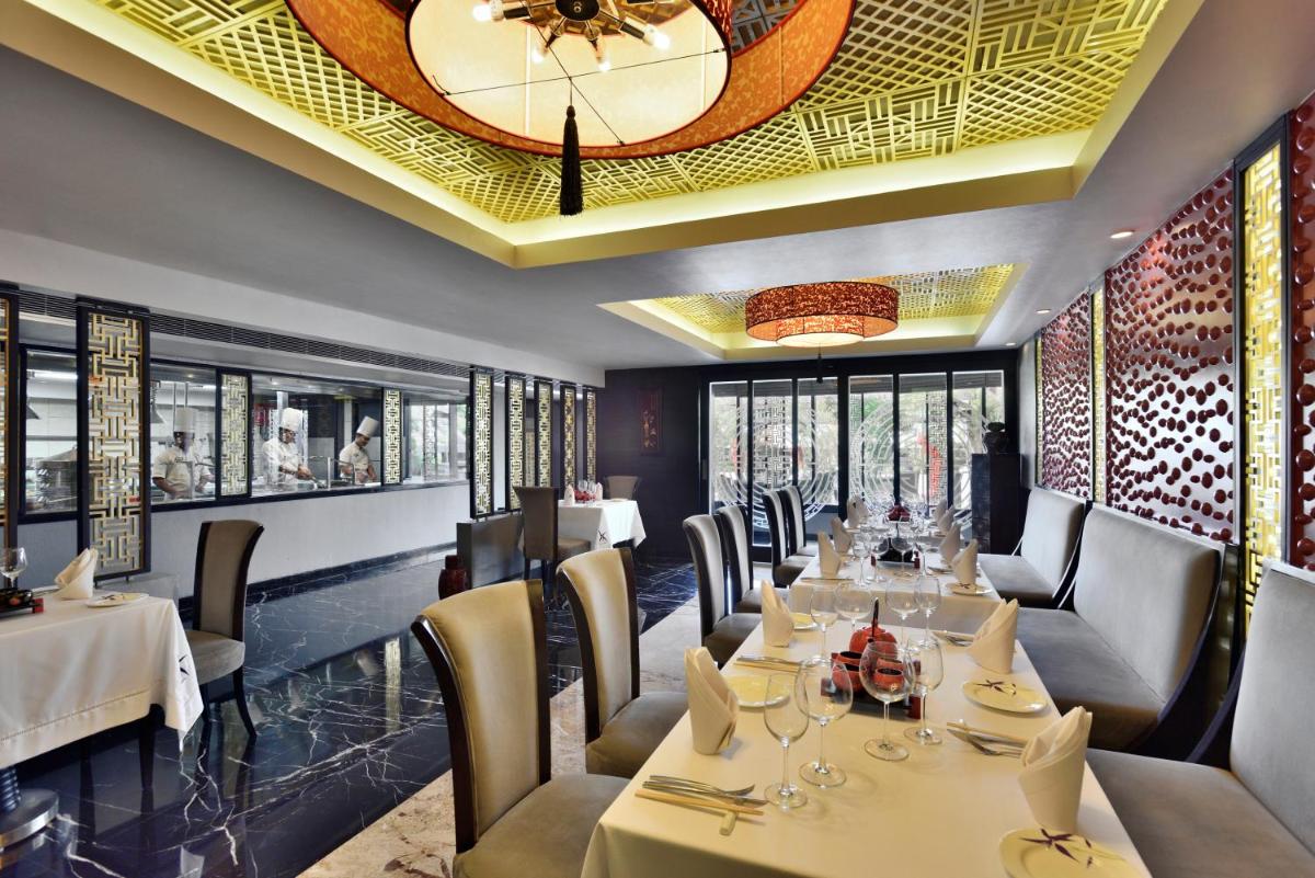 a restaurant with tables and chairs and a ceiling at Radisson Blu Hotel, Indore in Indore