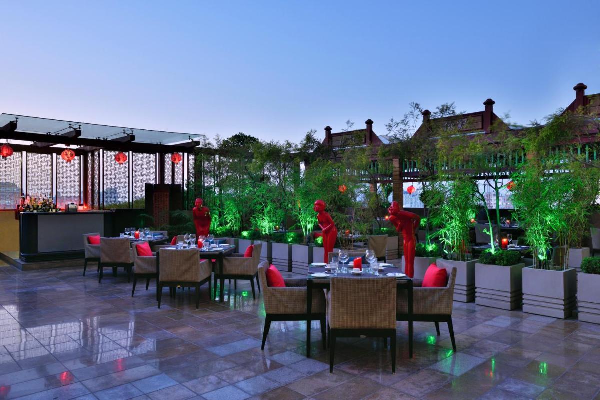 a dining area with tables and chairs and red statues at Radisson Blu Hotel, Indore in Indore