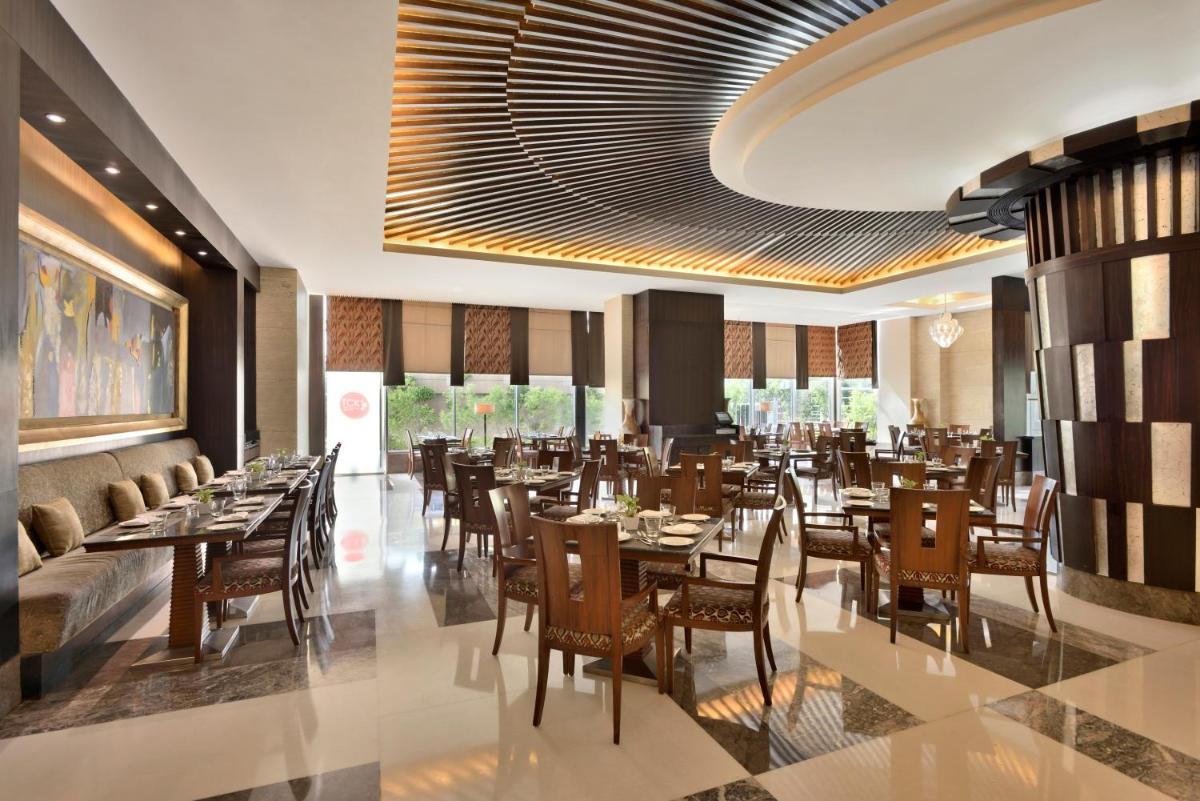 a restaurant with tables and chairs in a room at Radisson Blu Hotel, Indore in Indore