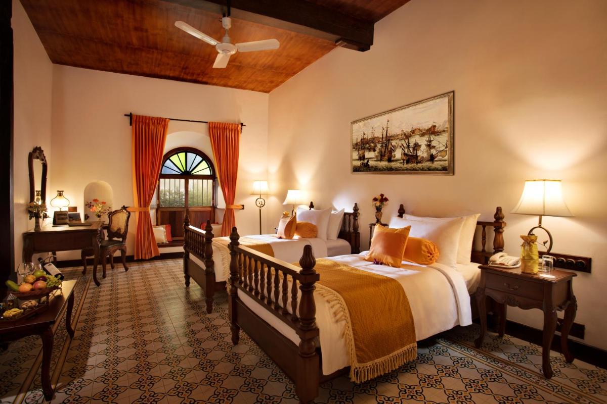 a bedroom with two beds and a desk and a window at Forte Kochi in Cochin