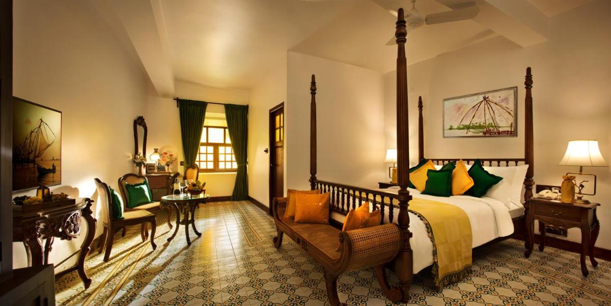 a bedroom with a bed and a chair and a table at Forte Kochi in Cochin