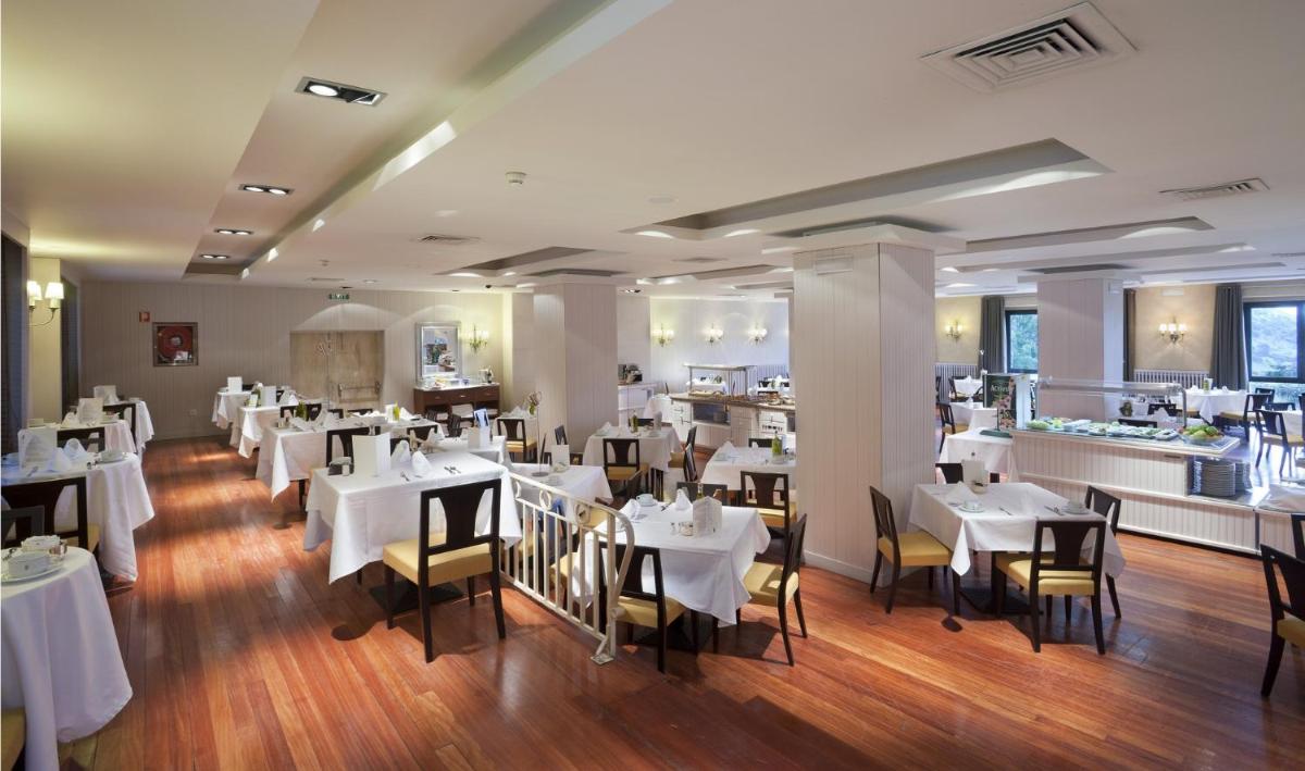 Un comedor con mesas y sillas blancas. en Parador de Vielha, en Vielha