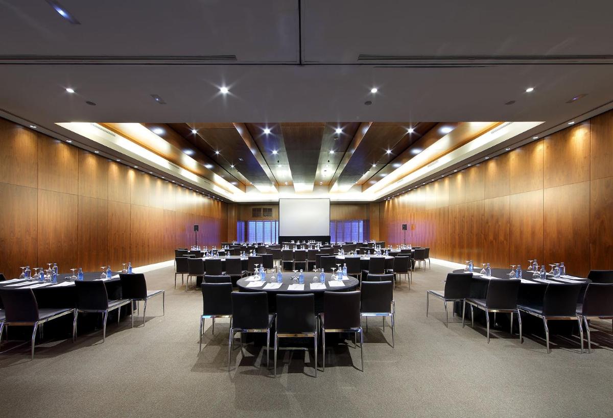 Una sala de conferencias con mesas, sillas y una pantalla. en Eurostars Madrid Tower, en Madrid