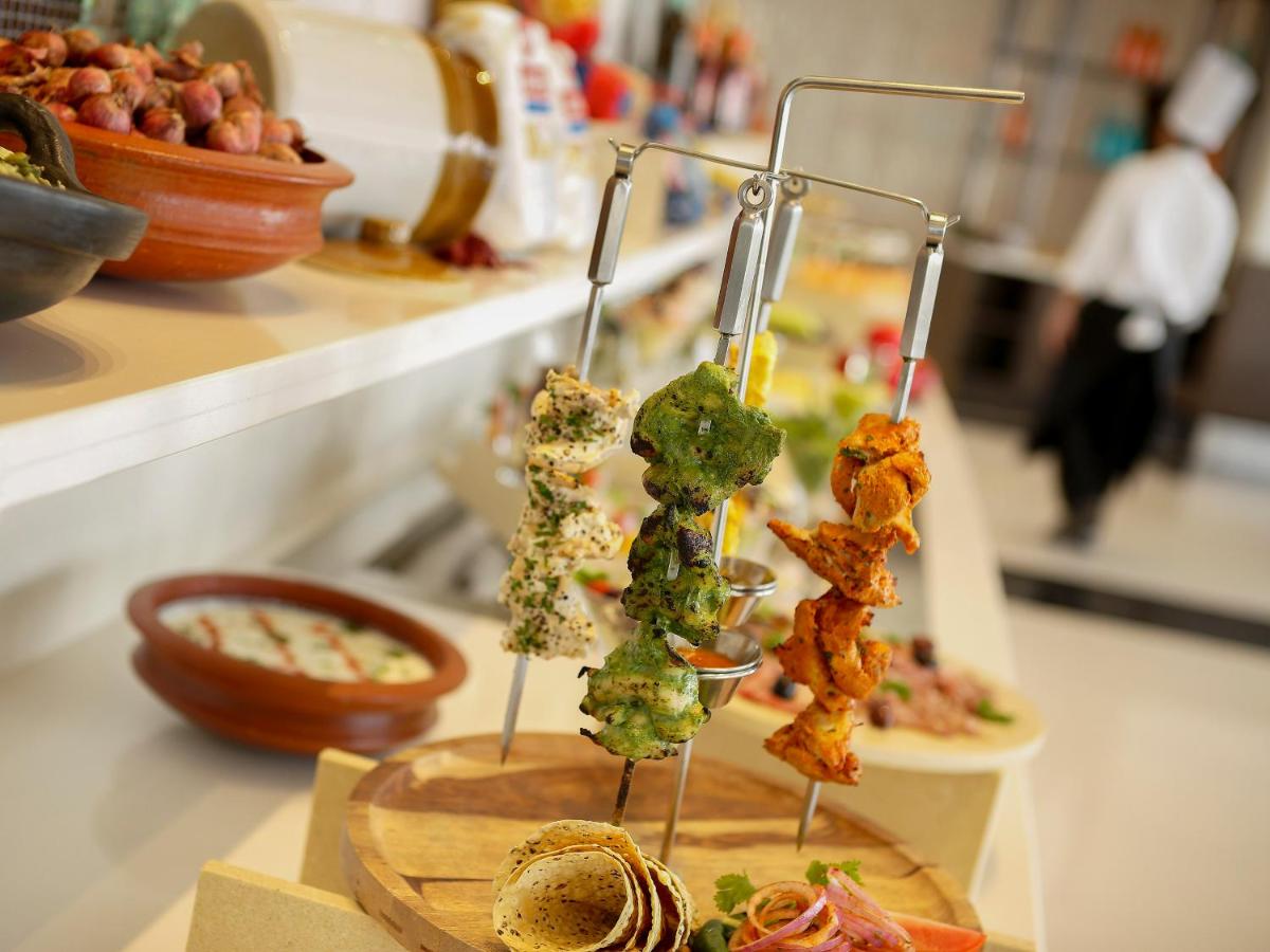 a bunch of food on skewers on a counter at Novotel Kochi Infopark in Cochin