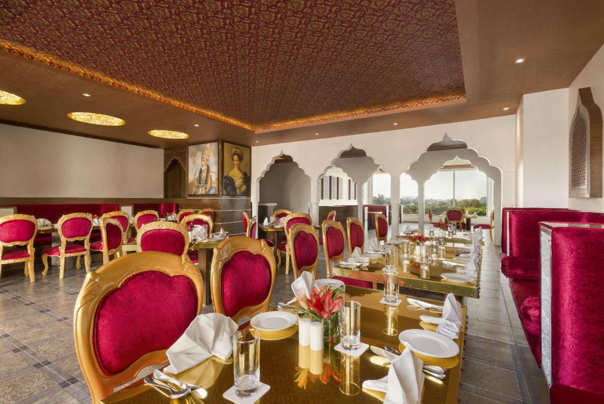 a restaurant with tables and chairs in a room at Saura Hotel, Agra - A Club Mahindra Associate in Agra