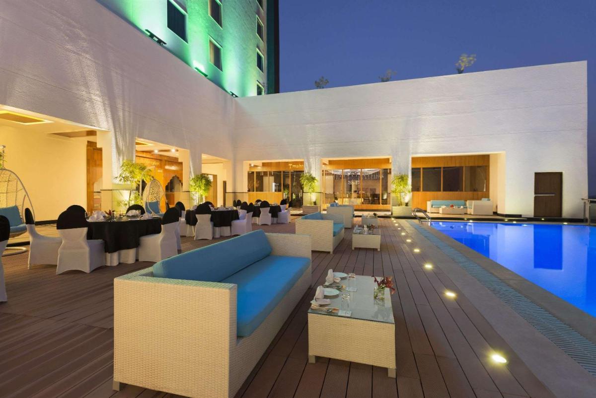 a living room with a blue couch and a pool at Saura Hotel, Agra - A Club Mahindra Associate in Agra