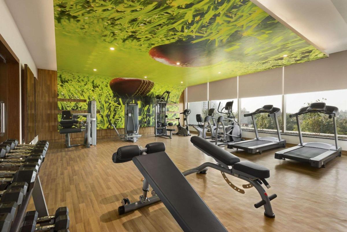 a gym with exercise equipment and a painting on the ceiling at Saura Hotel, Agra - A Club Mahindra Associate in Agra