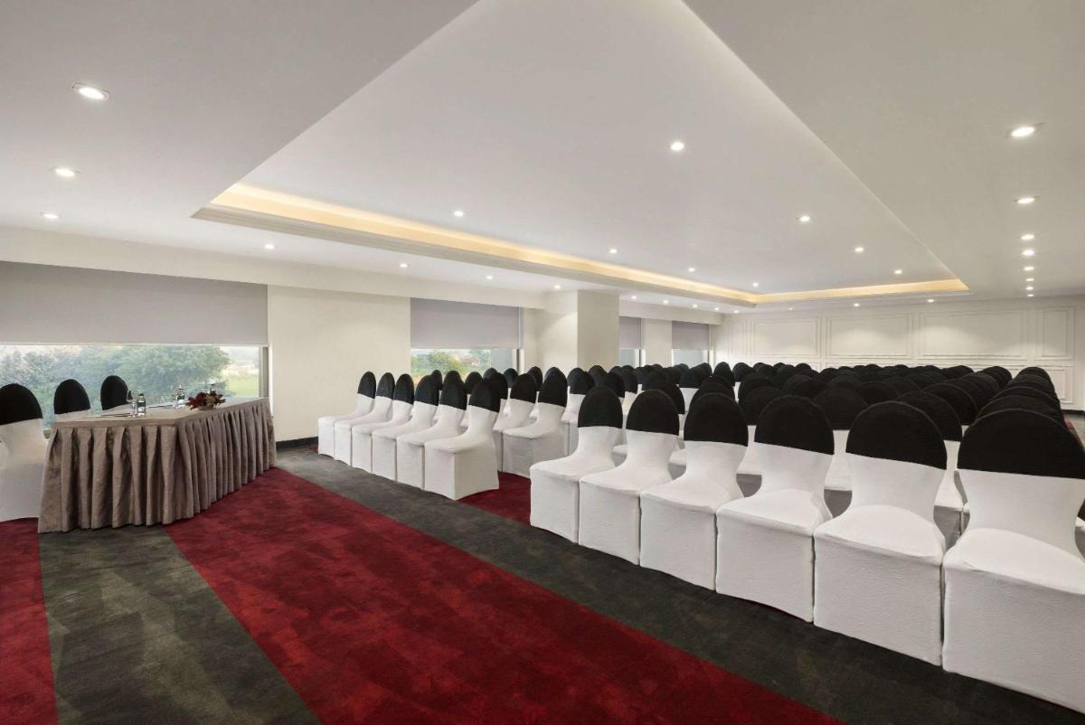 a conference room with white chairs and a red carpet at Saura Hotel, Agra - A Club Mahindra Associate in Agra