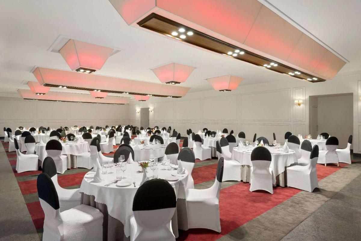 a banquet hall with white tables and chairs at Saura Hotel, Agra - A Club Mahindra Associate in Agra