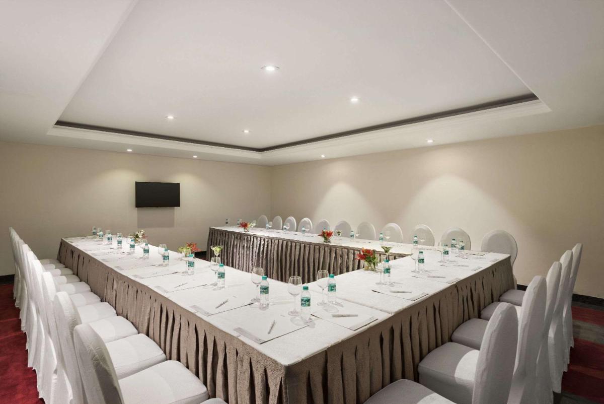 a long table in a room with white chairs at Saura Hotel, Agra - A Club Mahindra Associate in Agra