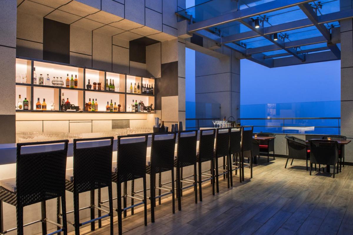 a restaurant with a bar with chairs and a table at Hyatt Regency Lucknow Gomti Nagar in Lucknow