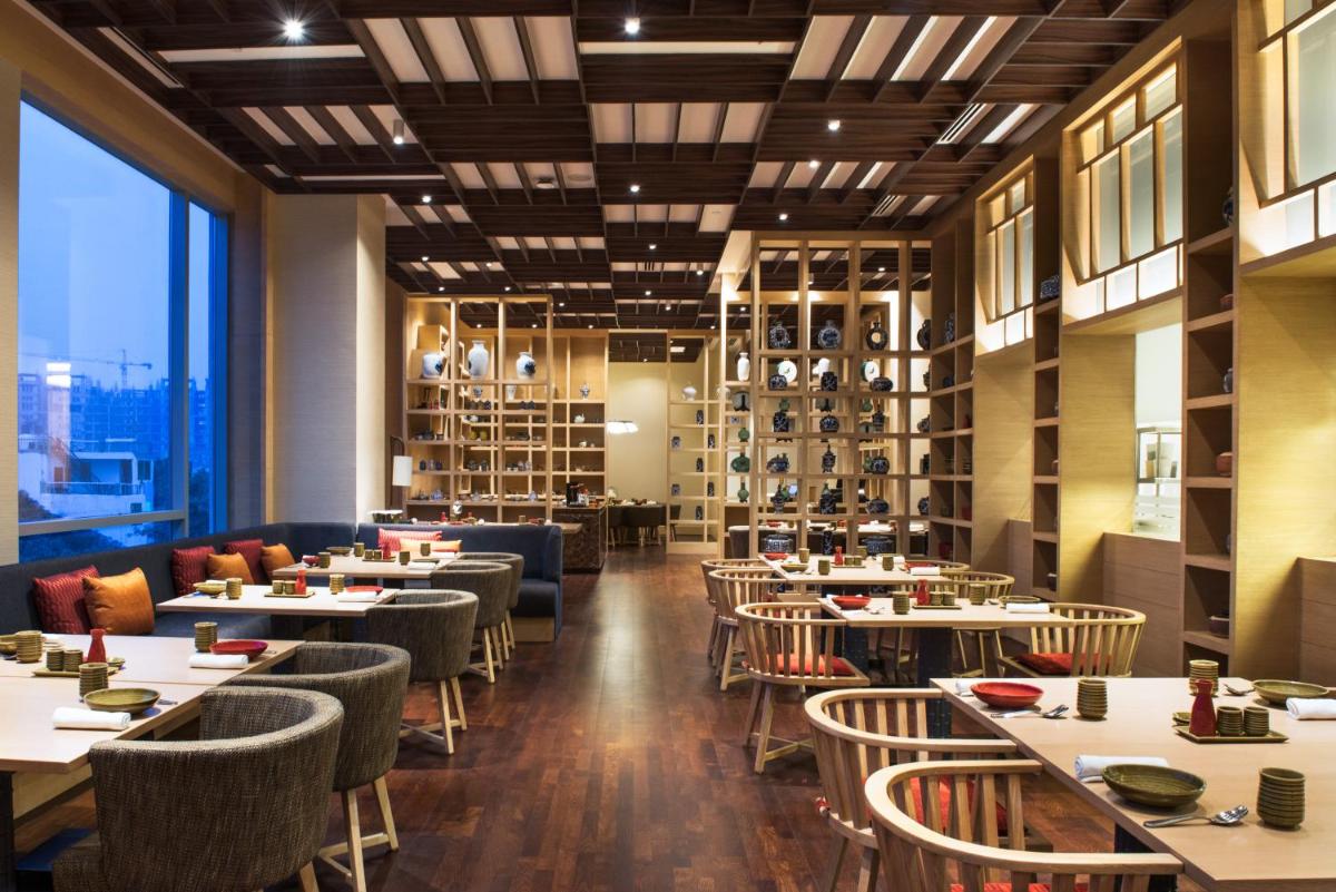 a restaurant with tables and chairs and a large window at Hyatt Regency Lucknow Gomti Nagar in Lucknow