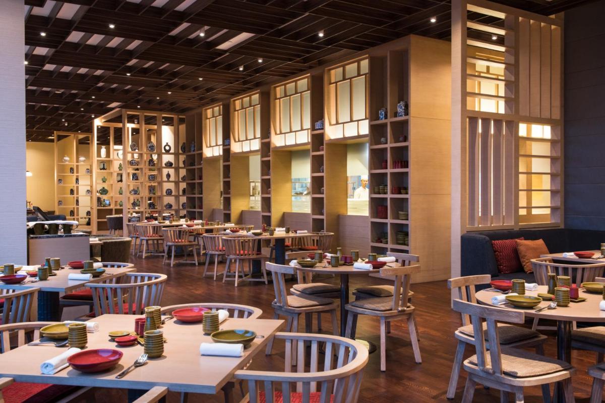 a dining room with tables and chairs andwindows at Hyatt Regency Lucknow Gomti Nagar in Lucknow