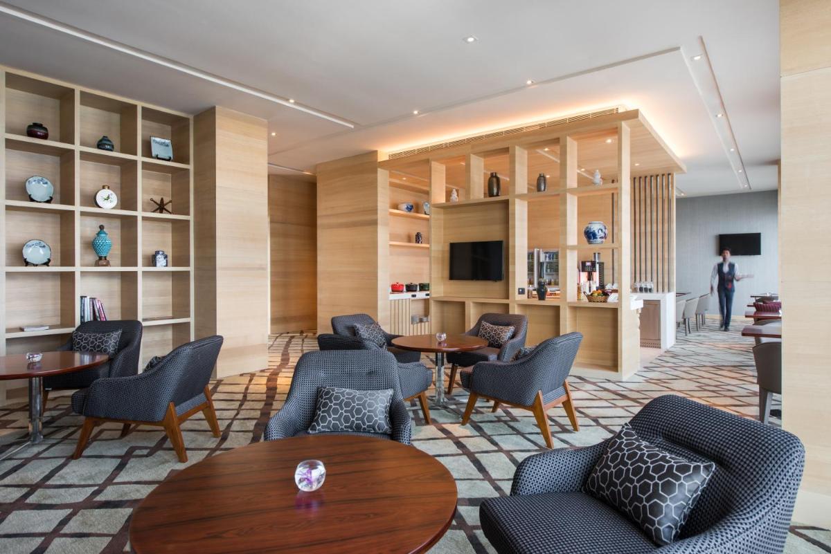 a hotel lobby with tables and chairs and shelves at Hyatt Regency Lucknow Gomti Nagar in Lucknow
