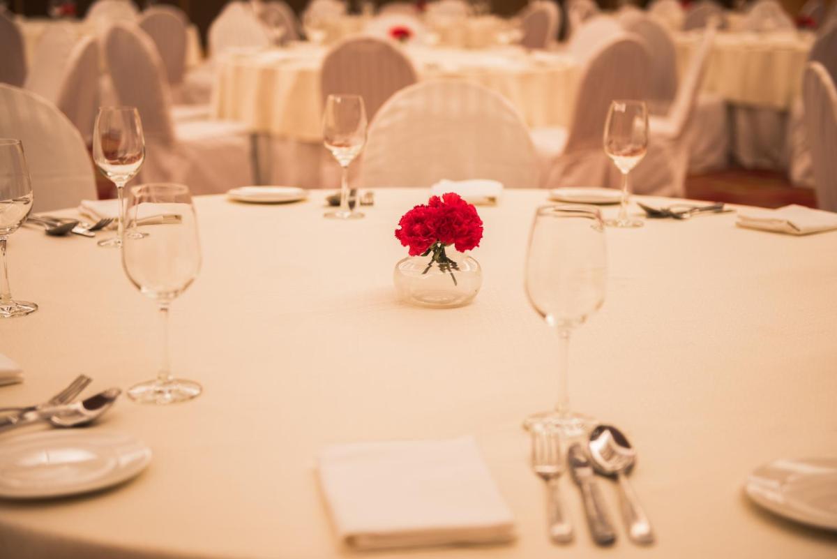 a table with glasses and a red flower in a vase at Hyatt Regency Lucknow Gomti Nagar in Lucknow