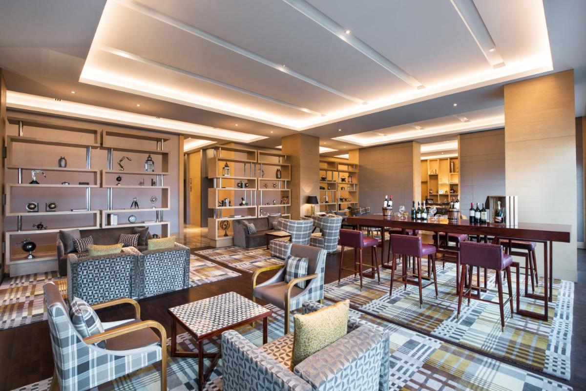 a restaurant with a bar and tables and chairs at Hyatt Regency Lucknow Gomti Nagar in Lucknow