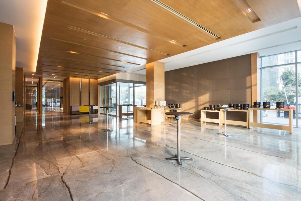 a lobby with tables and chairs in a building at Hyatt Regency Lucknow Gomti Nagar in Lucknow