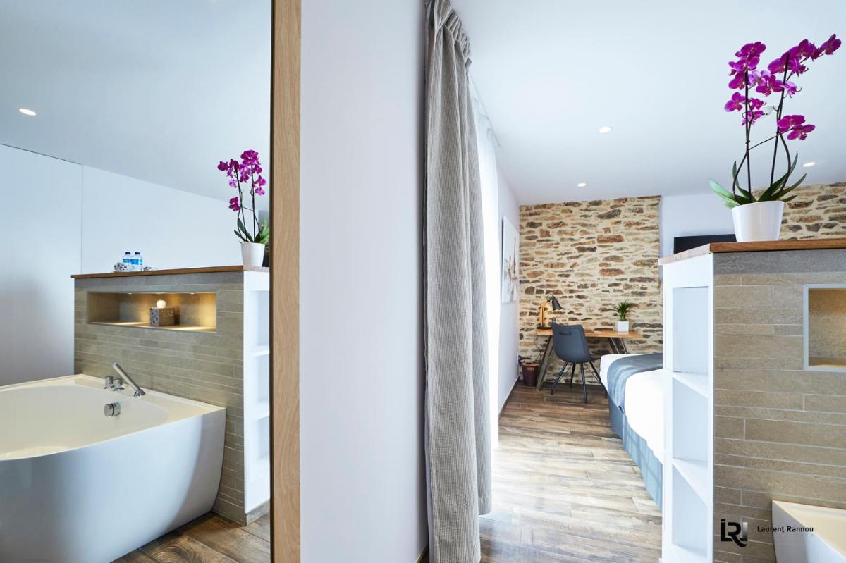 une salle de bain avec une baignoire et un lavabo dans une pièce dans l'établissement Le Manoir de Kerbot, à Sarzeau