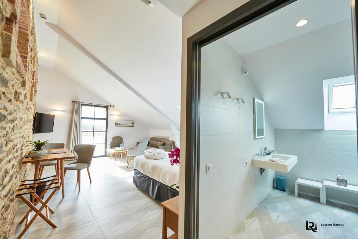 une chambre avec un lit, un bureau et une table dans l'établissement Le Manoir de Kerbot, à Sarzeau
