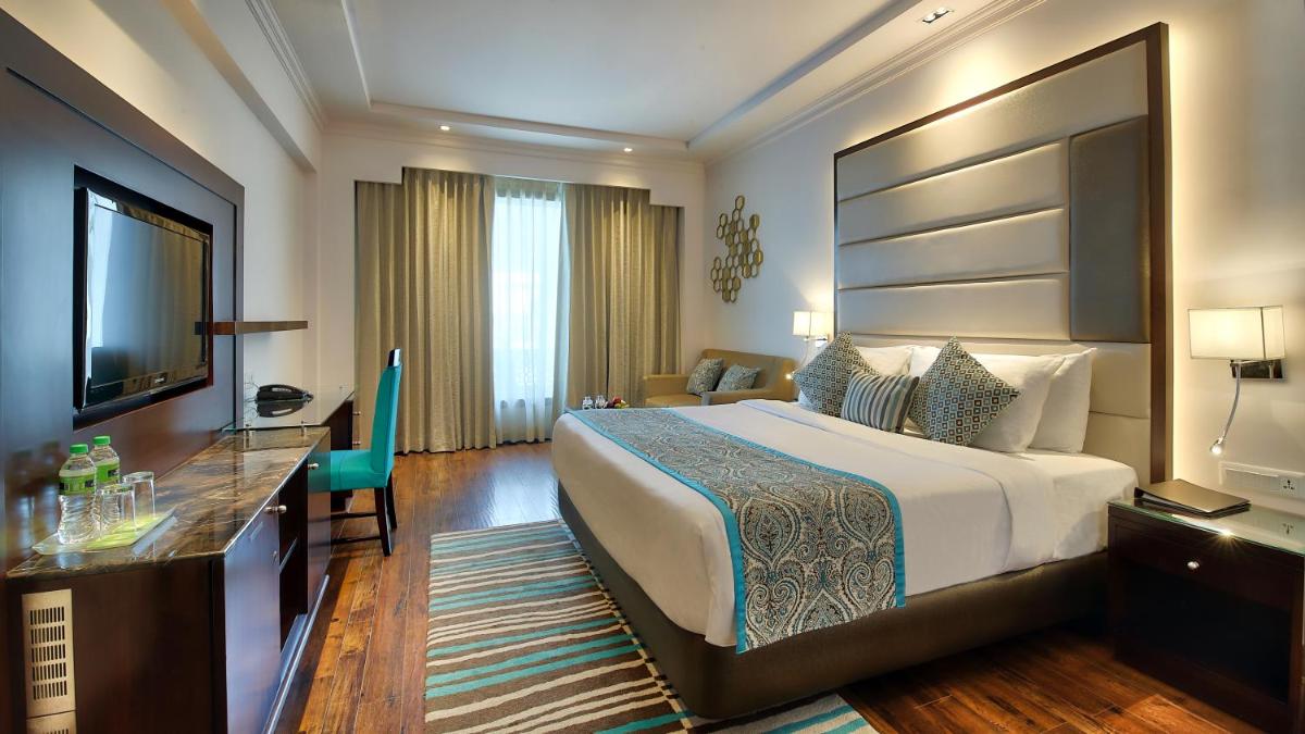 a hotel room with a large bed and a television at Radisson Jaipur City Center in Jaipur
