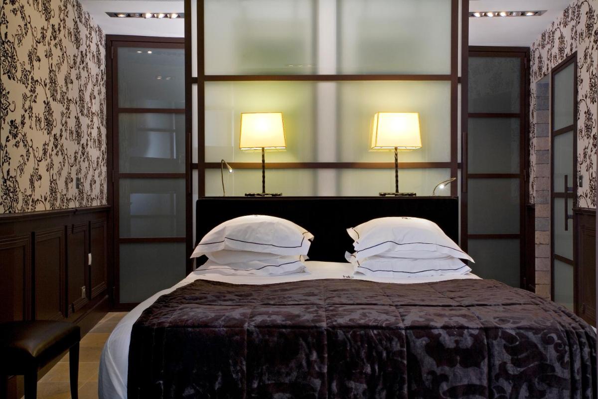 une chambre avec un lit avec deux oreillers et deux lampes dans l'établissement Hôtel du Château & Spa - Teritoria, à Carcassonne 94 autres photos