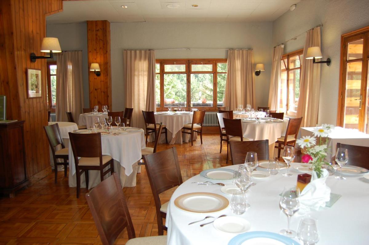 Un comedor con mesas y sillas blancas. en Hotel Manantial, en Caldes de Boí