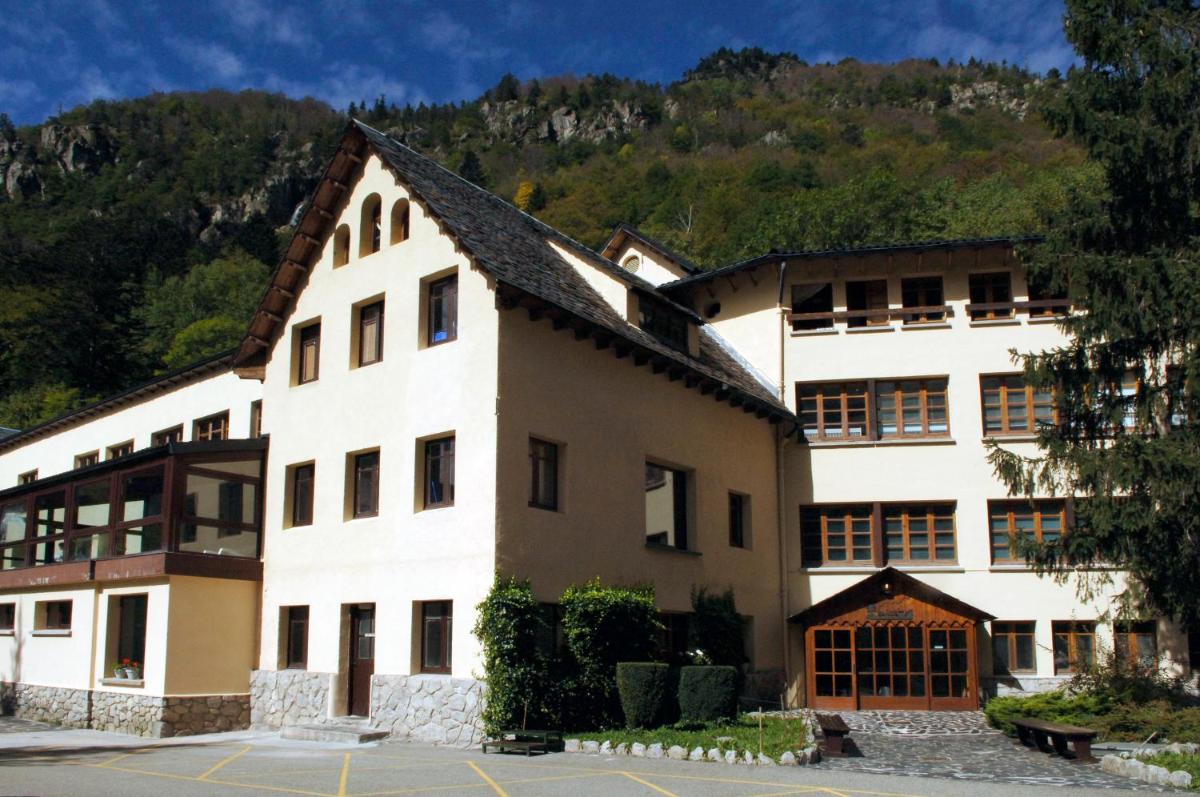 un gran edificio blanco con una montaña en el fondo en Hotel Caldas, en Caldes de Boí
