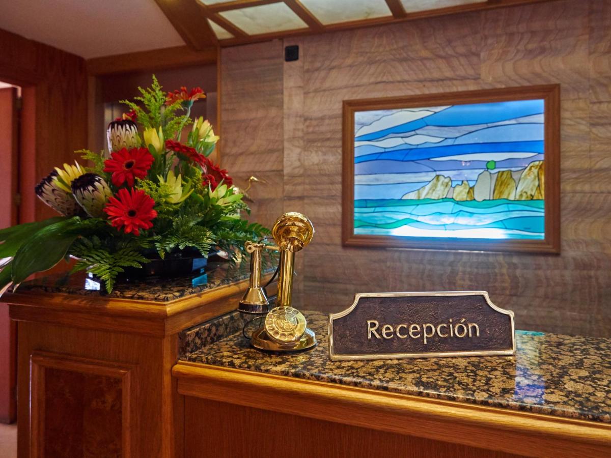 Un mostrador de recepción con flores y un cartel que dice recepción. en Hotel Petit Cala Fornells, en Paguera