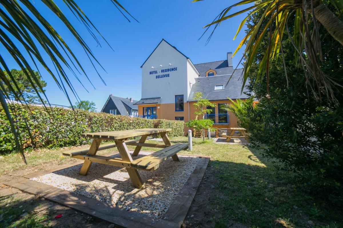 une table de pique-nique en bois devant un bâtiment dans l'établissement Résidence Bellevue, à Camaret-sur-Mer