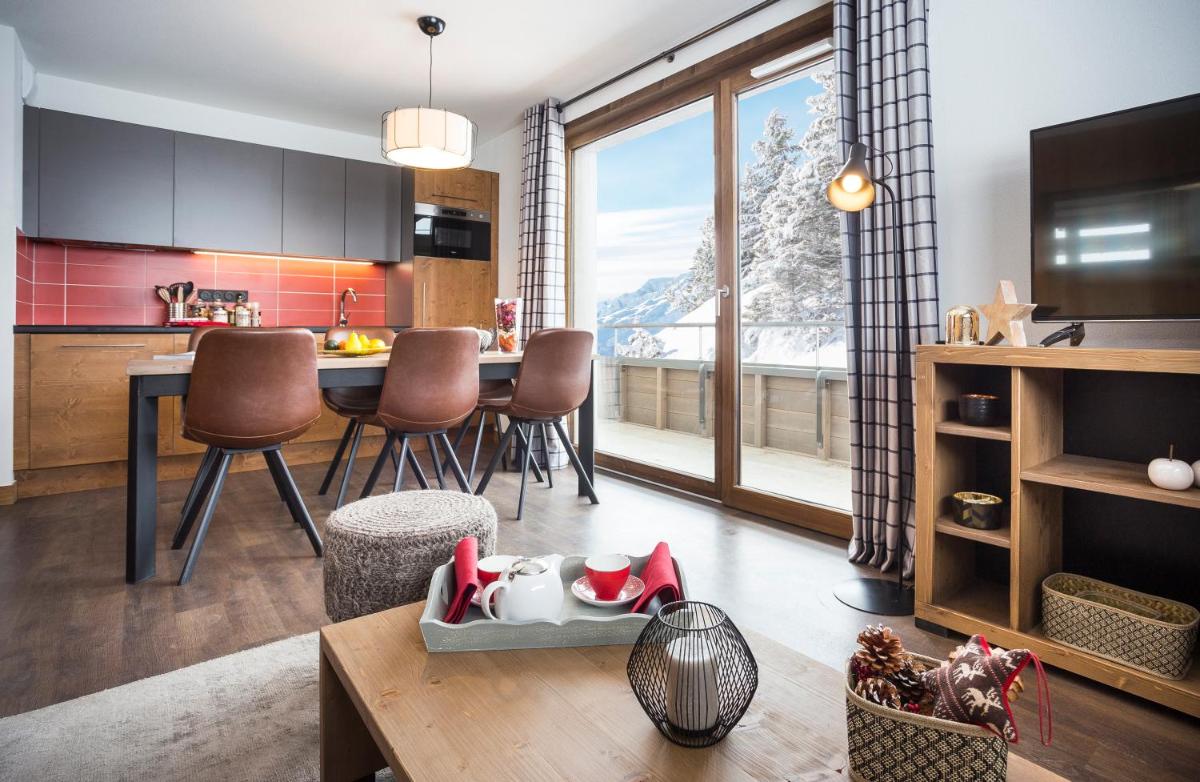 une cuisine et un salon avec une table et des chaises dans l'établissement Résidence Club MMV Les Chalets des Cimes, aux Saisies