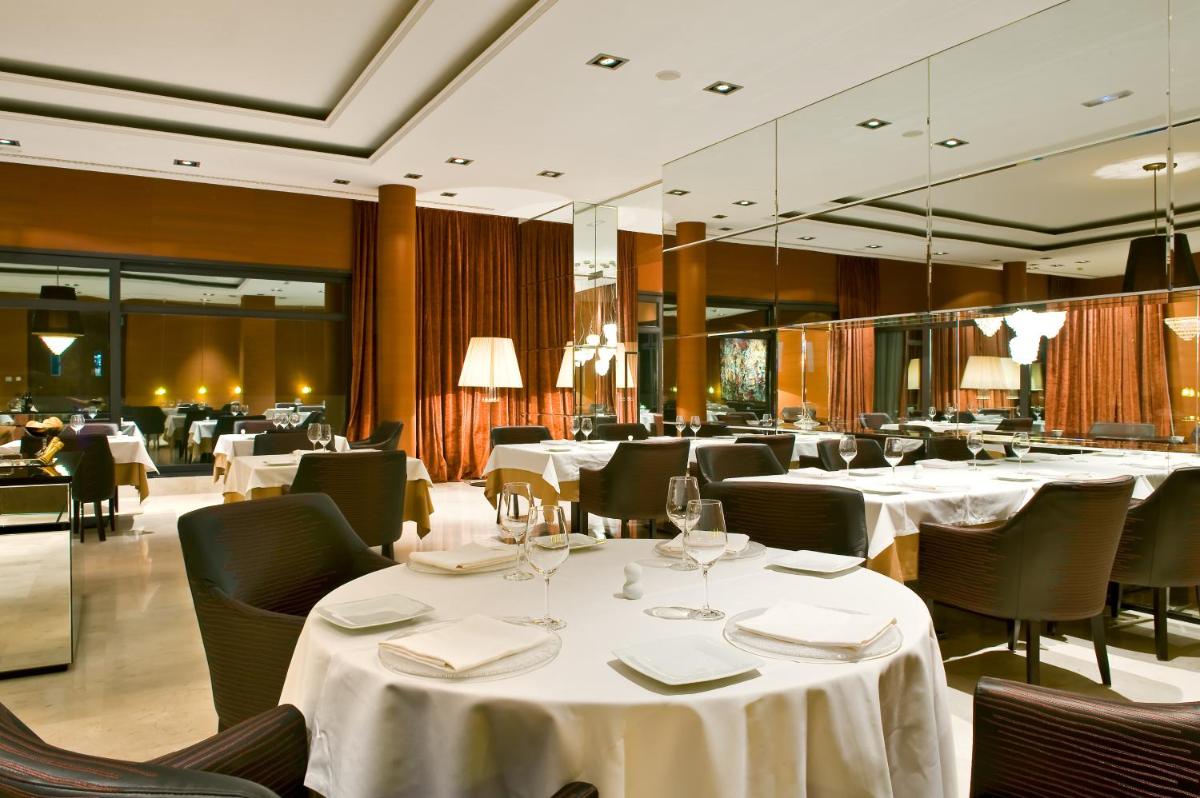 Un restaurante con mesas y sillas con manteles blancos. en URH Hotel Spa Zen Balagares, en Overo