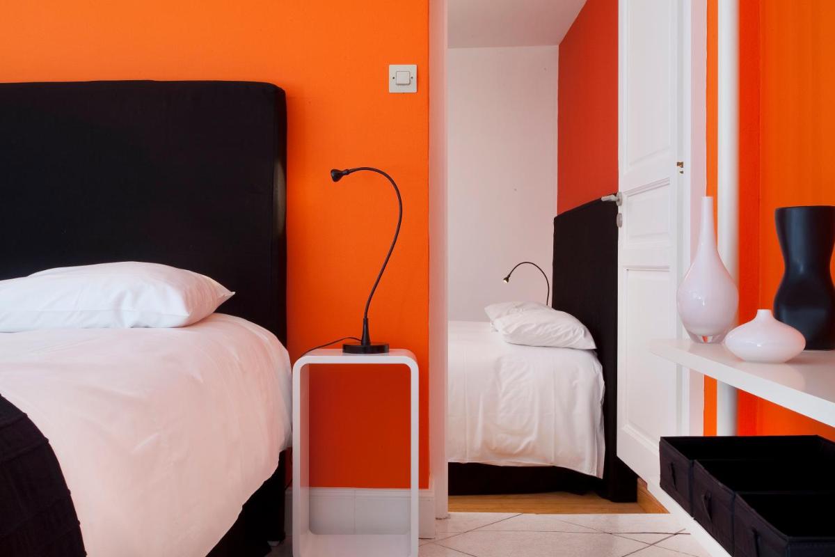 une chambre avec un lit et une valise rouge dans l'établissement Hôtel De L'octroi, à Carcassonne