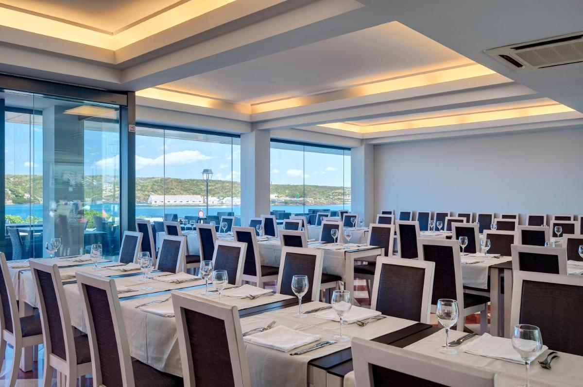 una sala de conferencias con mesas y sillas blancas y ventanas en Barceló Hamilton Menorca - Adults Only, en Es Castell