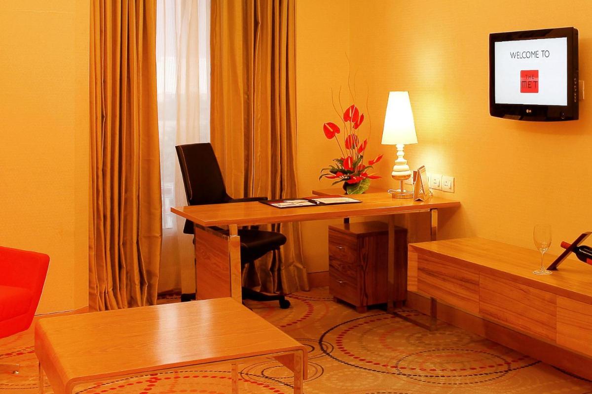 a hotel room with a desk and a table with a lamp at The Metropolitan Hotel & Spa New Delhi in New Delhi