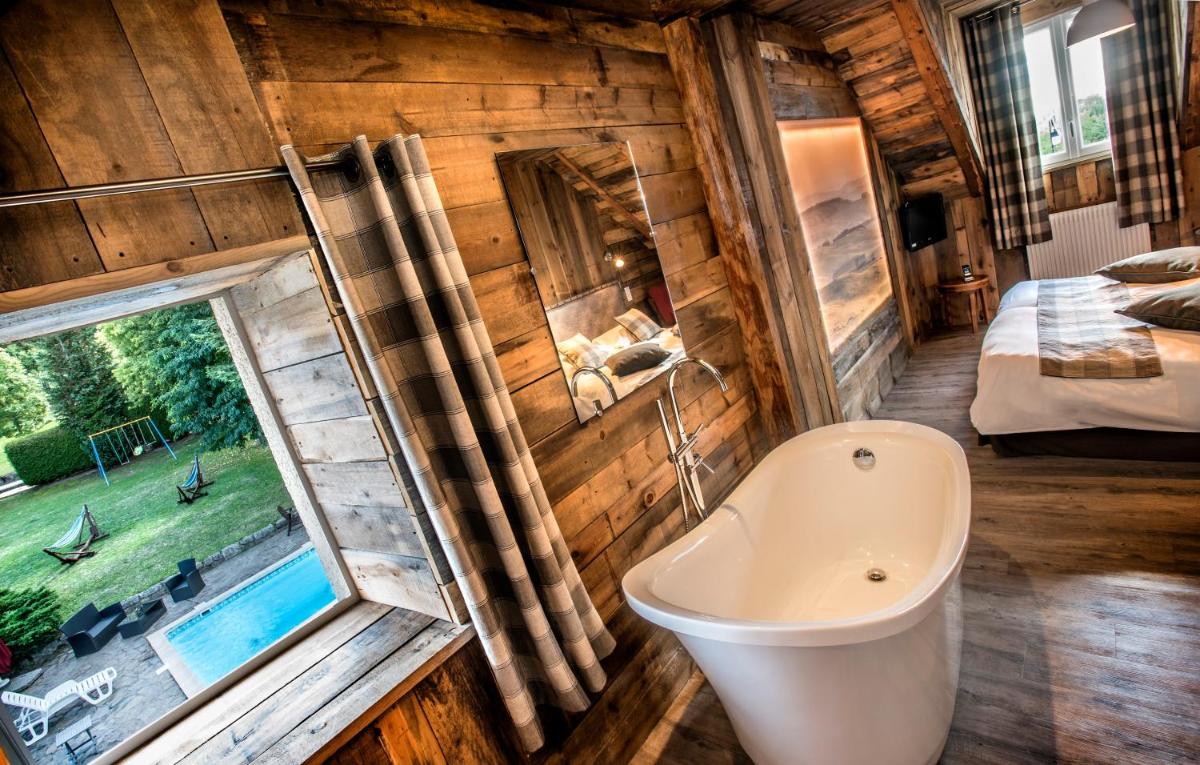 La salle de bains est pourvue d'une baignoire, d'une fenêtre et d'un lit. dans l'établissement Hotel Le Rocher Blanc, à Albaret-Sainte-Marie