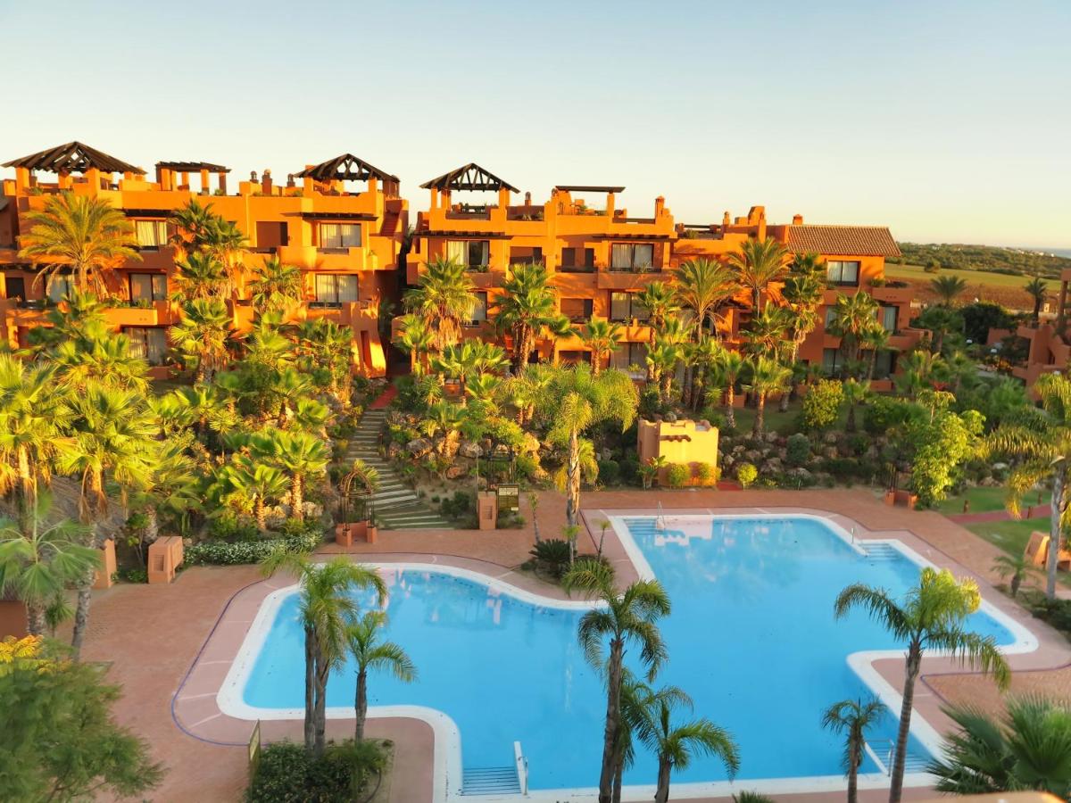 Una vista aérea de un resort con dos piscinas y palmeras. en Aparthotel Novo Resort, en Chiclana de la Frontera