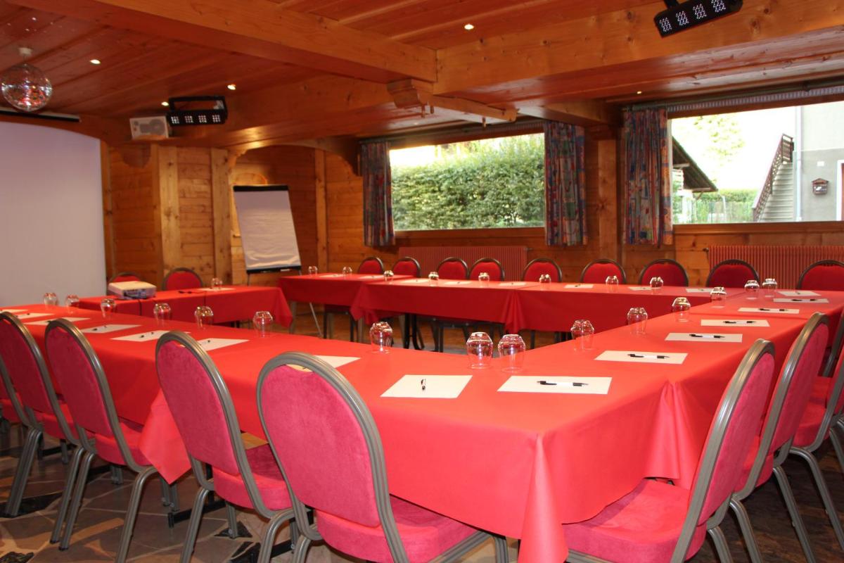 une salle de conférence avec des tables et des chaises rouges dans l'établissement Chalet-Hôtel Neige et Roc, The Originals Relais, à Samoëns 86 autres photos