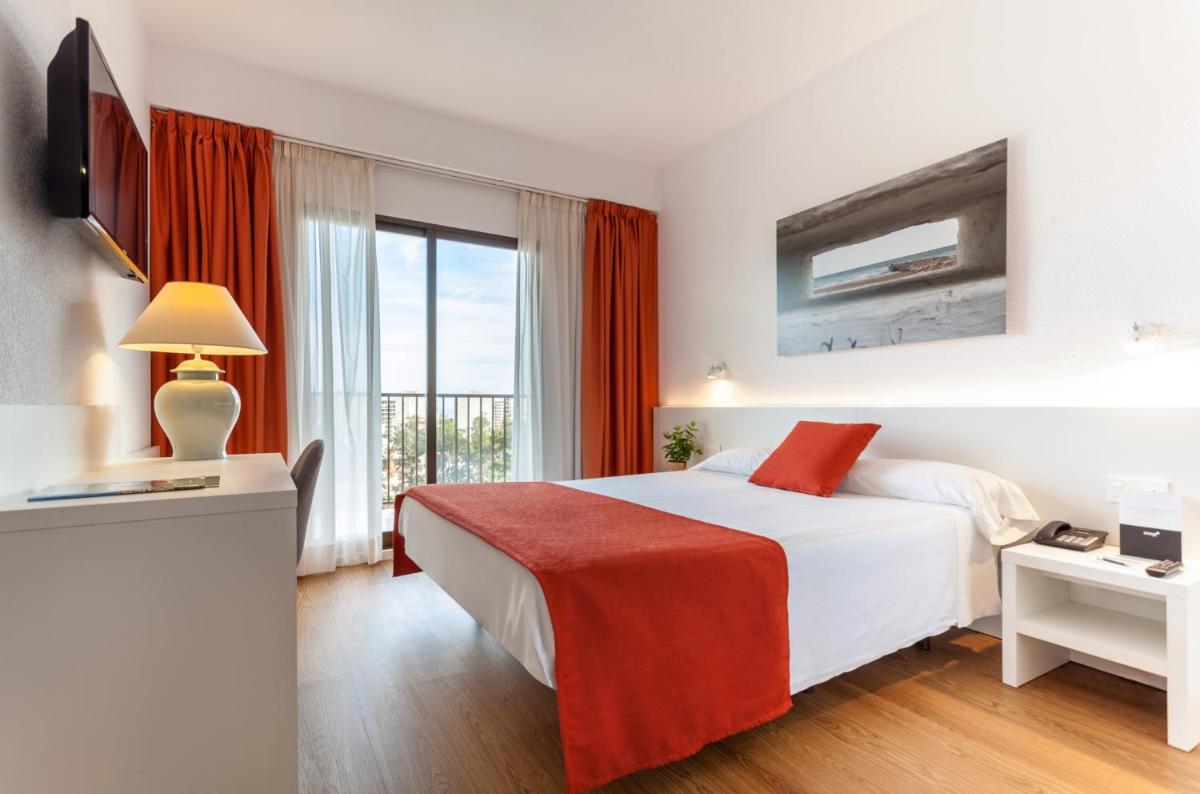 Una habitación de hotel con una cama y una ventana grande. en Intelier Orange, en Benicàssim