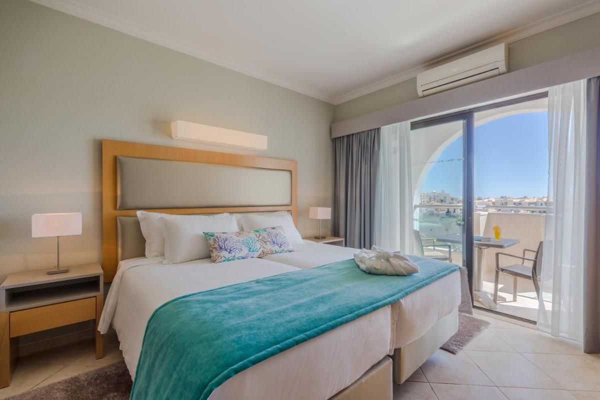 um quarto com uma cama grande e uma janela grande em The Navigator - Solaqua em Albufeira um quarto com uma cama grande e uma janela grande em The Navigator - Solaqua em Albufeira