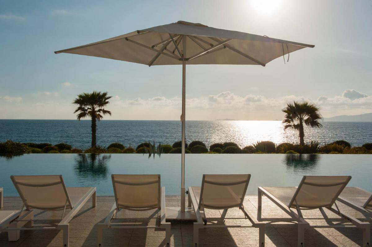 - un groupe de chaises et un parasol à côté de la piscine dans l'établissement Radisson Blu Resort & Spa, Ajaccio Bay, à Porticcio
