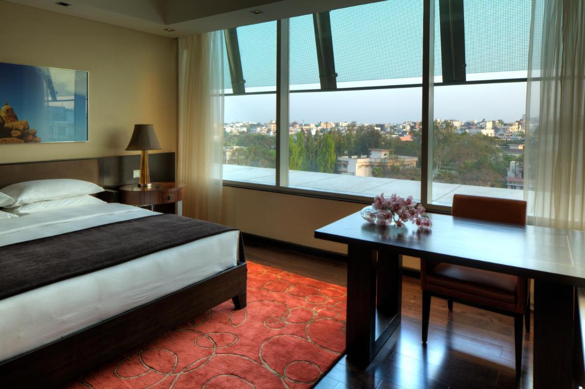 a bedroom with a bed and a desk with a large window at Park Hyatt Hotel and Residences, Hyderabad in Hyderabad