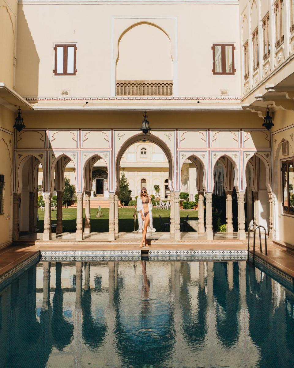 a woman sitting in a pool in a building at The Raj Palace (Small Luxury Hotels of the World) in Jaipur