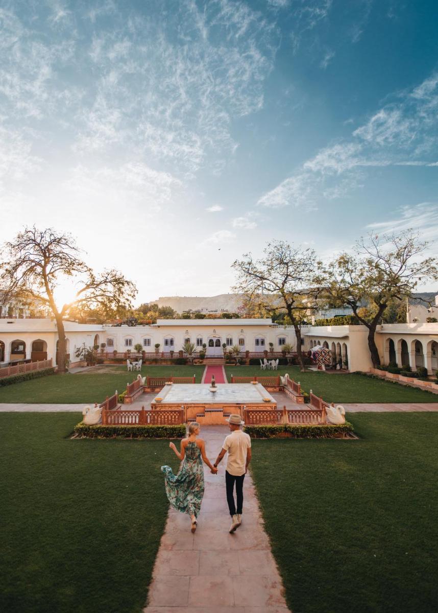 a man and a woman walking through a courtyard at The Raj Palace (Small Luxury Hotels of the World) in Jaipur
