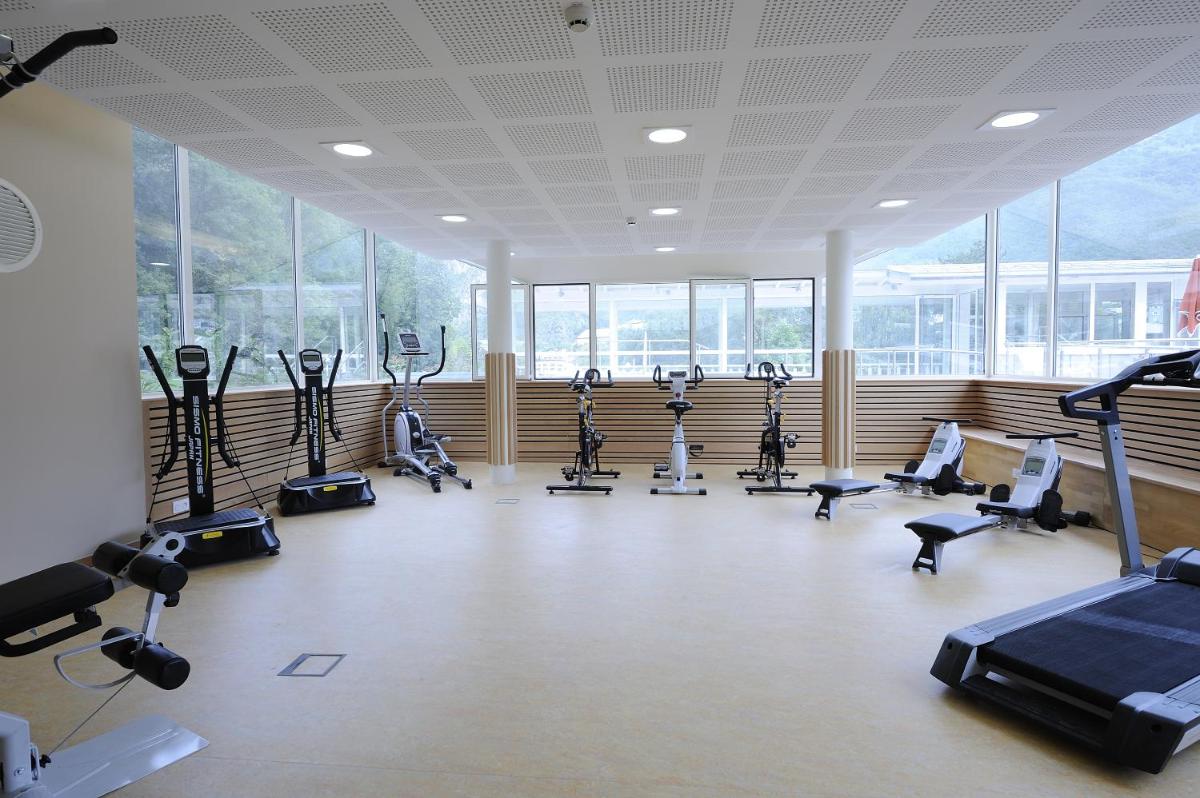 une salle de sport avec plusieurs tapis de course et vélos d'exercice dans l'établissement Residence RADIANA, à La Léchère