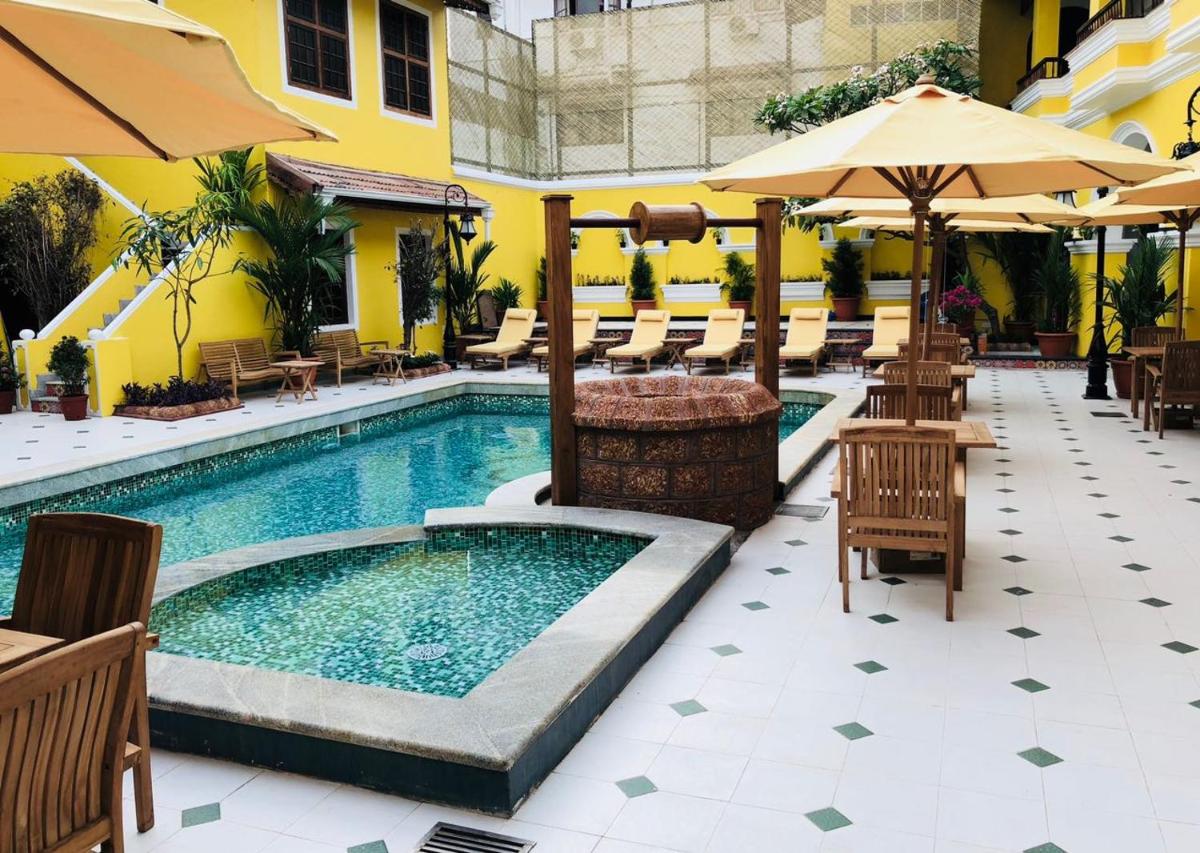 a swimming pool with tables and chairs and umbrellas at Forte Kochi in Cochin