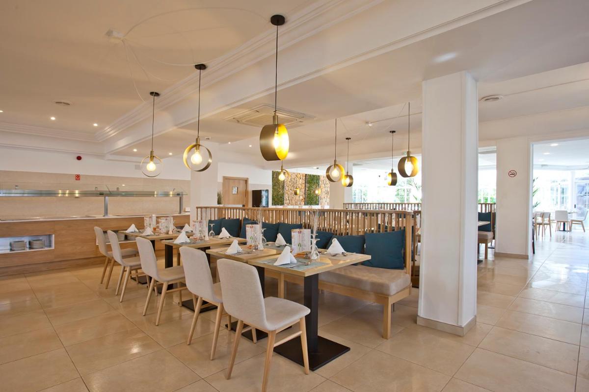 Un comedor con una mesa larga y sillas. en Bahía de Alcudia Hotel & Spa, en Puerto de Alcudia