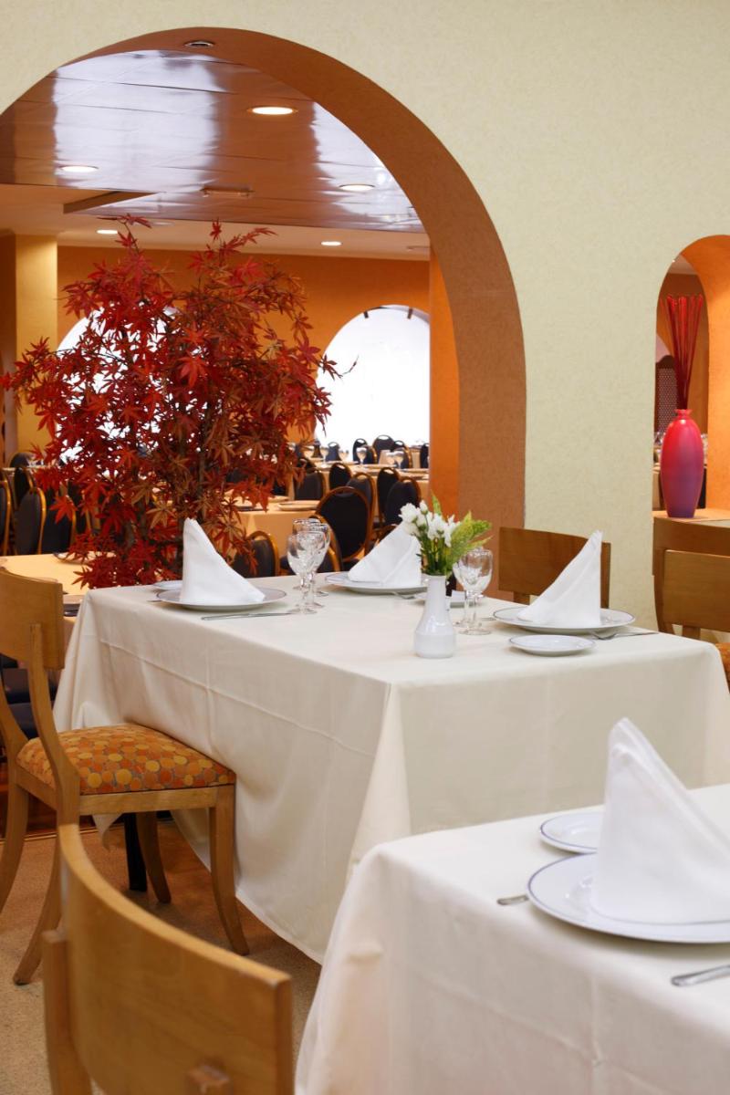 un comedor con mesas blancas y sillas con flores en Hotel Spa Congreso, en Teo