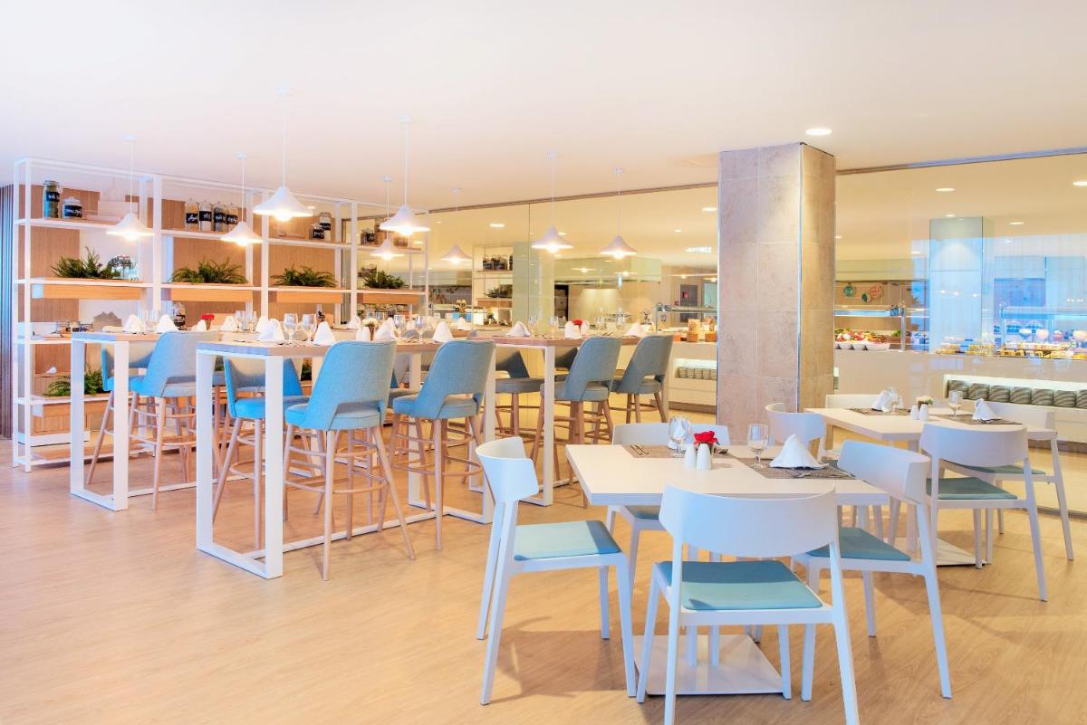 un restaurante con mesas blancas y sillas azules en Iberostar Waves Playa de Muro, en Playa de Muro