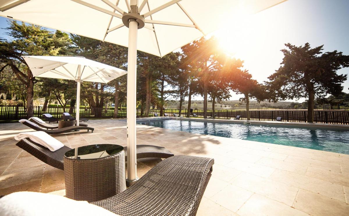 - une piscine avec des chaises et un parasol à côté de la piscine dans l'établissement Château L'Hospitalet Wine Resort Beach & Spa, à Narbonne