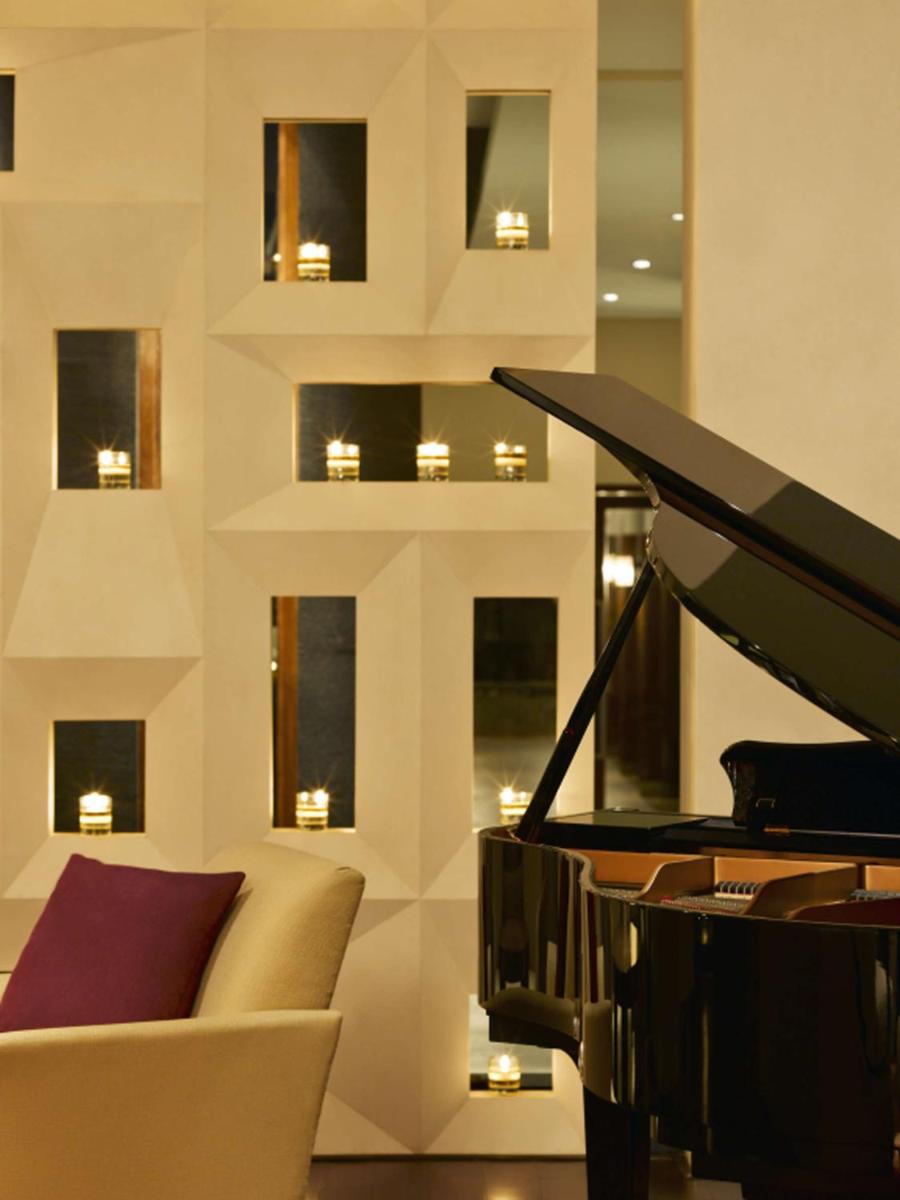 a living room with a couch and a piano at Hyatt Hyderabad Gachibowli in Hyderabad
